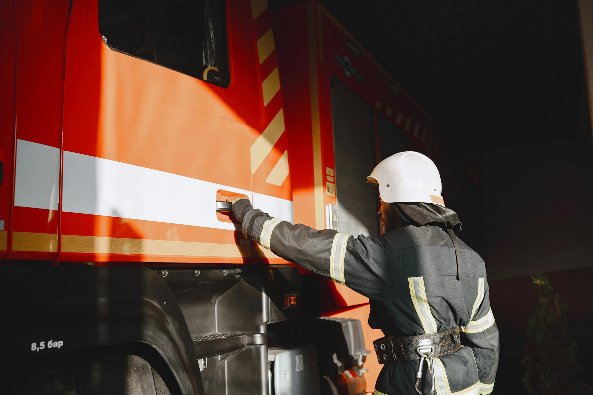 A Man in Safety Gear Opening the Door of the Fire Truck