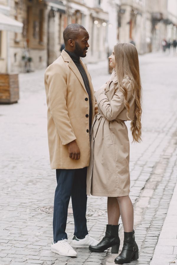 A couple in winter coats talking on a cobblestone street