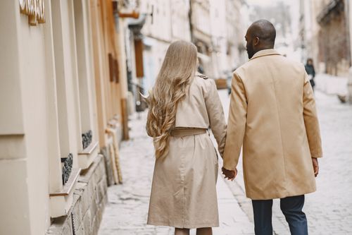Free A couple walking hand in hand on a city street in winter clothing, capturing warmth and love. Stock Photo