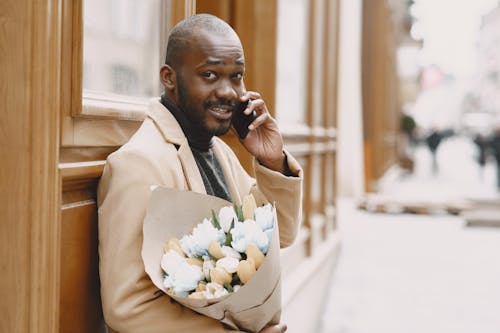 Free Man in Beige Coat carrying a Bouquet of Flowers  Stock Photo