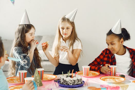 A group of children celebrating a birthday with party hats and cake indoors.