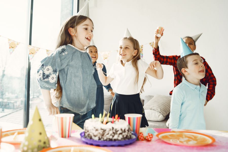 Kids having fun at a birthday party with hats, cake and balloons