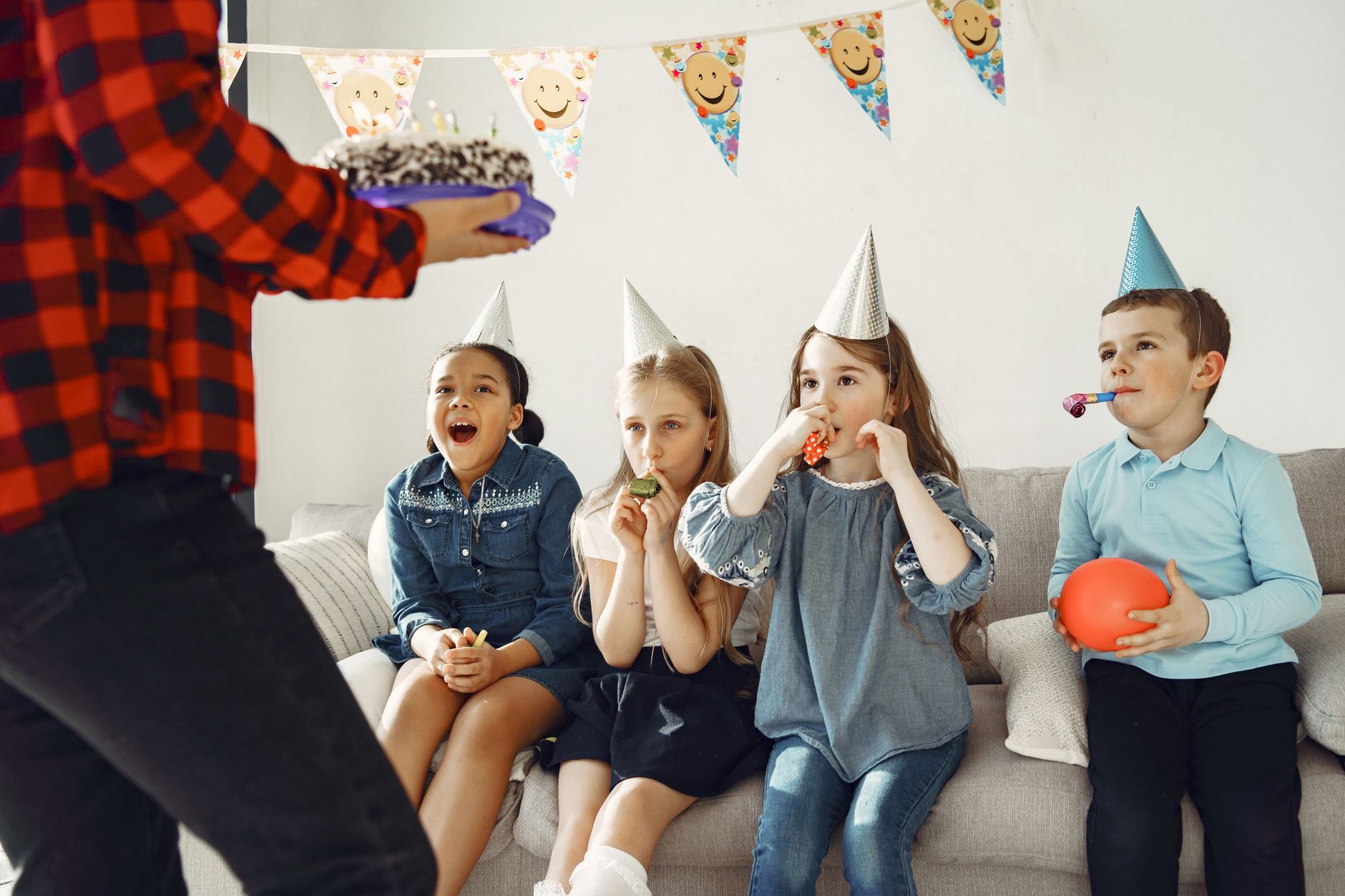 clown entertainer for birthday egypt — Happy kids wearing party hats eagerly await birthday cake indoors.