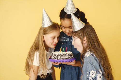 Free Kids Wearing Party Hats in Front of the Cake with Candles Stock Photo