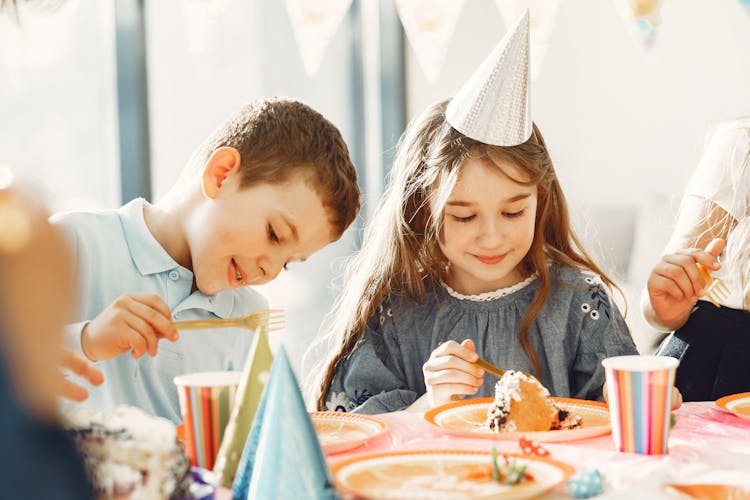 A Boy And A Girl Eating Cake At The Table