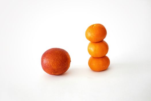 Three stacked oranges and a single blood orange on a white surface, bright contrasting colors.