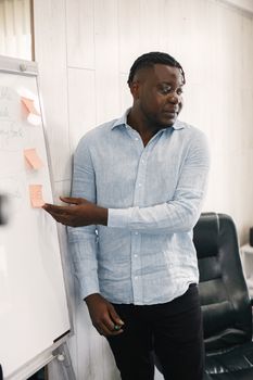 A man discusses ideas using sticky notes on a whiteboard in an office setting.