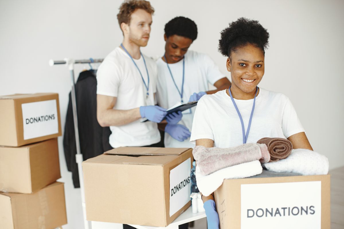 Benevole souriante portant un carton de dons pour une action solidaire