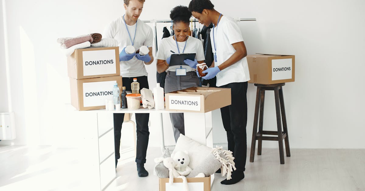 Three volunteers organize donation boxes filled with essentials in a bright indoor setting.