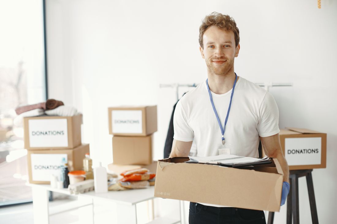 A smiling volunteer holding a box of donated goods