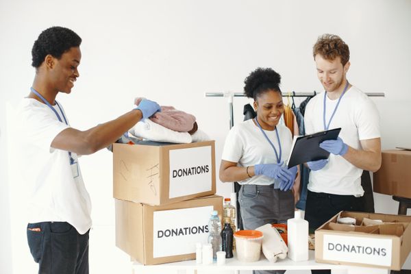 Volunteers sorting boxes labeled donations filled with clothing and household goods given away before a move