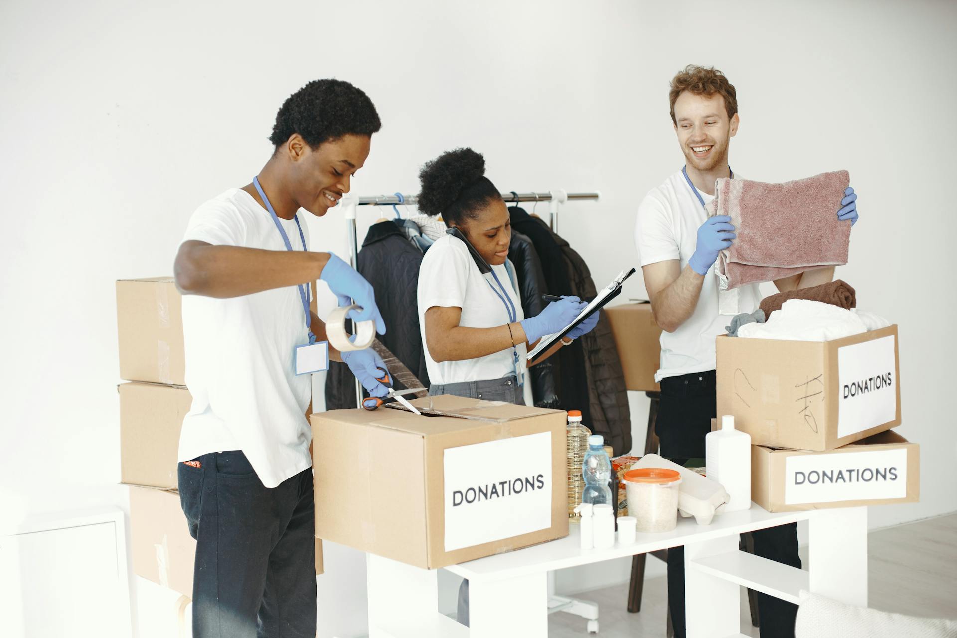 Diverse volunteers happily sorting donation boxes indoors during a charity event.