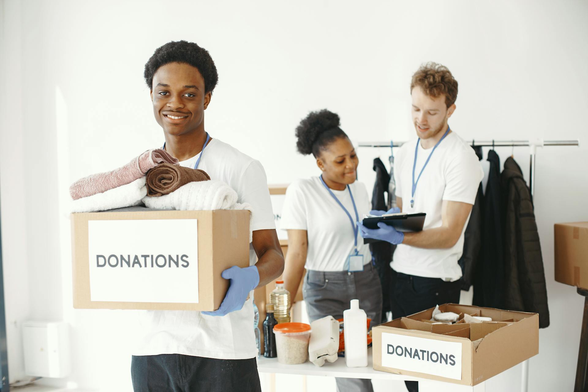 Diverse group of volunteers organizing donation boxes with clothes and supplies indoors.