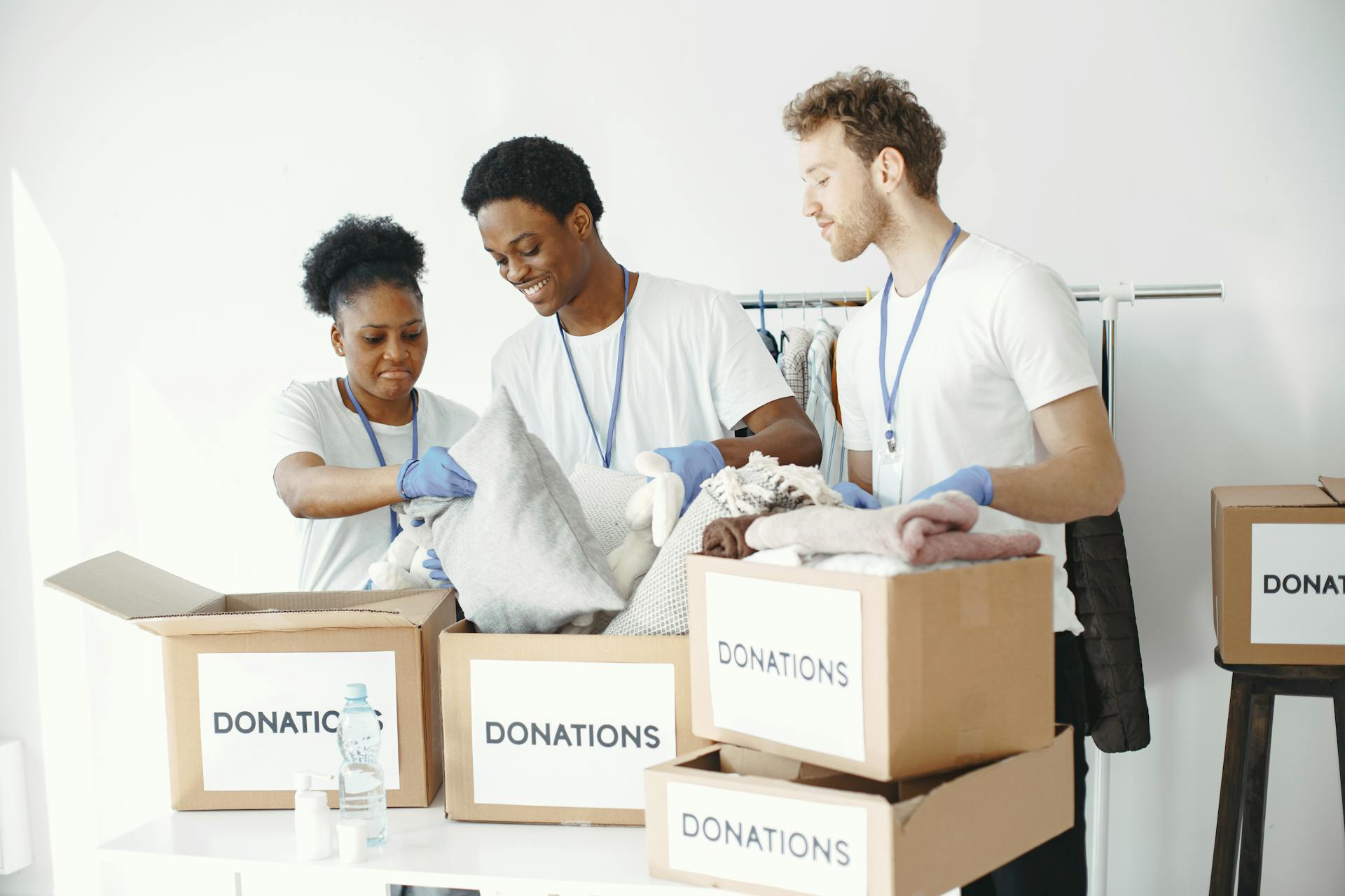 A diverse group of volunteers organizes donation boxes with clothing items indoors.