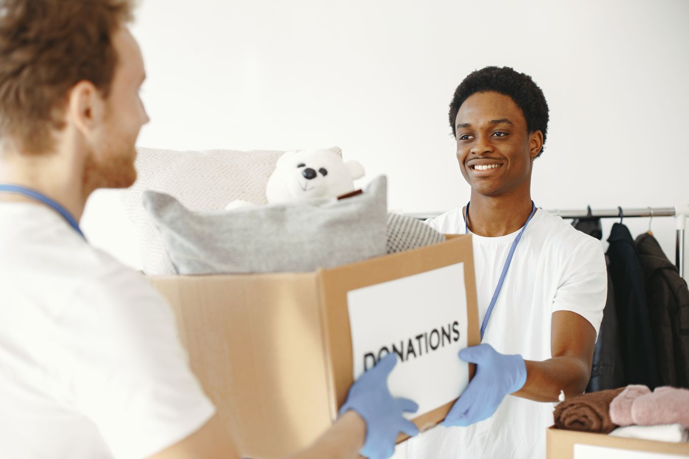 Two volunteers handing over a box of donated goods — photo by Gustavo Fring on Pexels