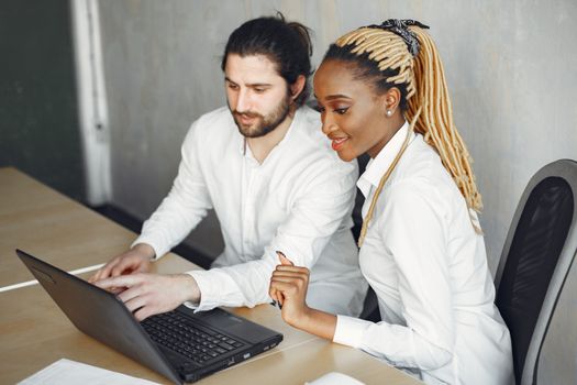 Two colleagues working together on a laptop in a modern office setting.