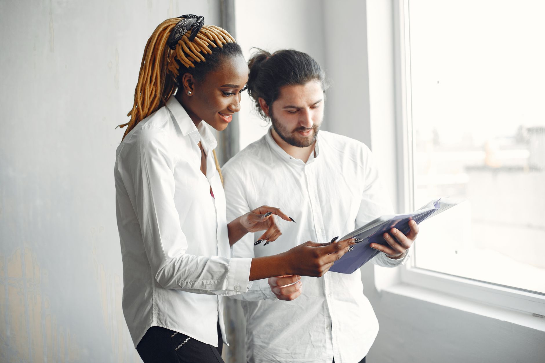 Two colleagues discussing documents in a bright office setting, promoting diversity.