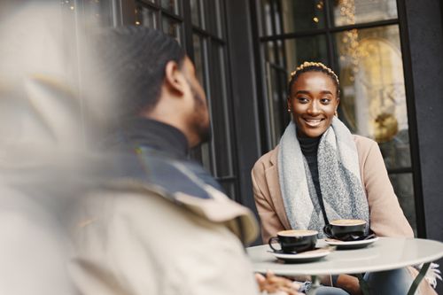 Free A joyful woman engaging in conversation at a stylish outdoor café setting. Stock Photo