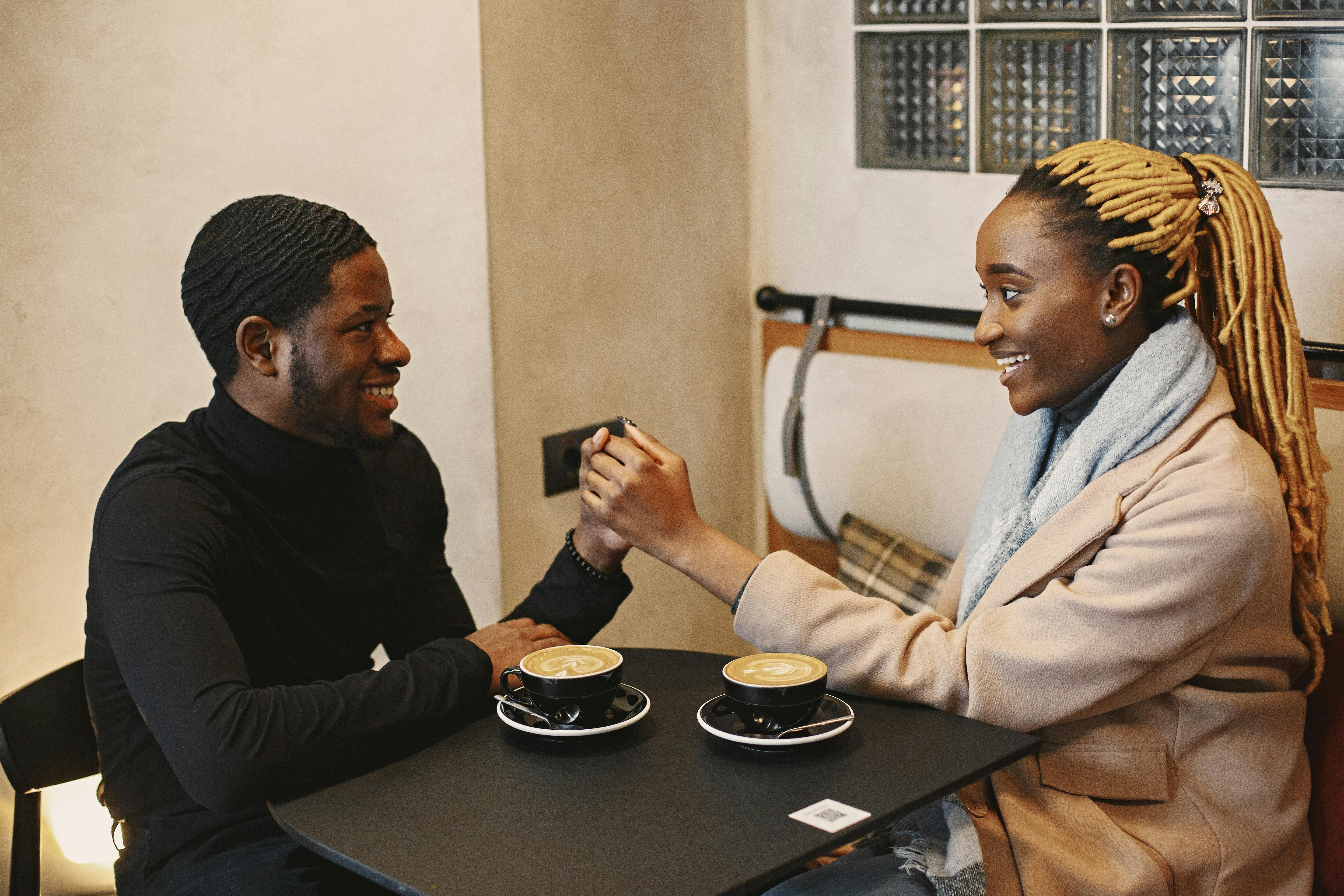 Happy couple holding hands over coffee in a cozy cafe setting.