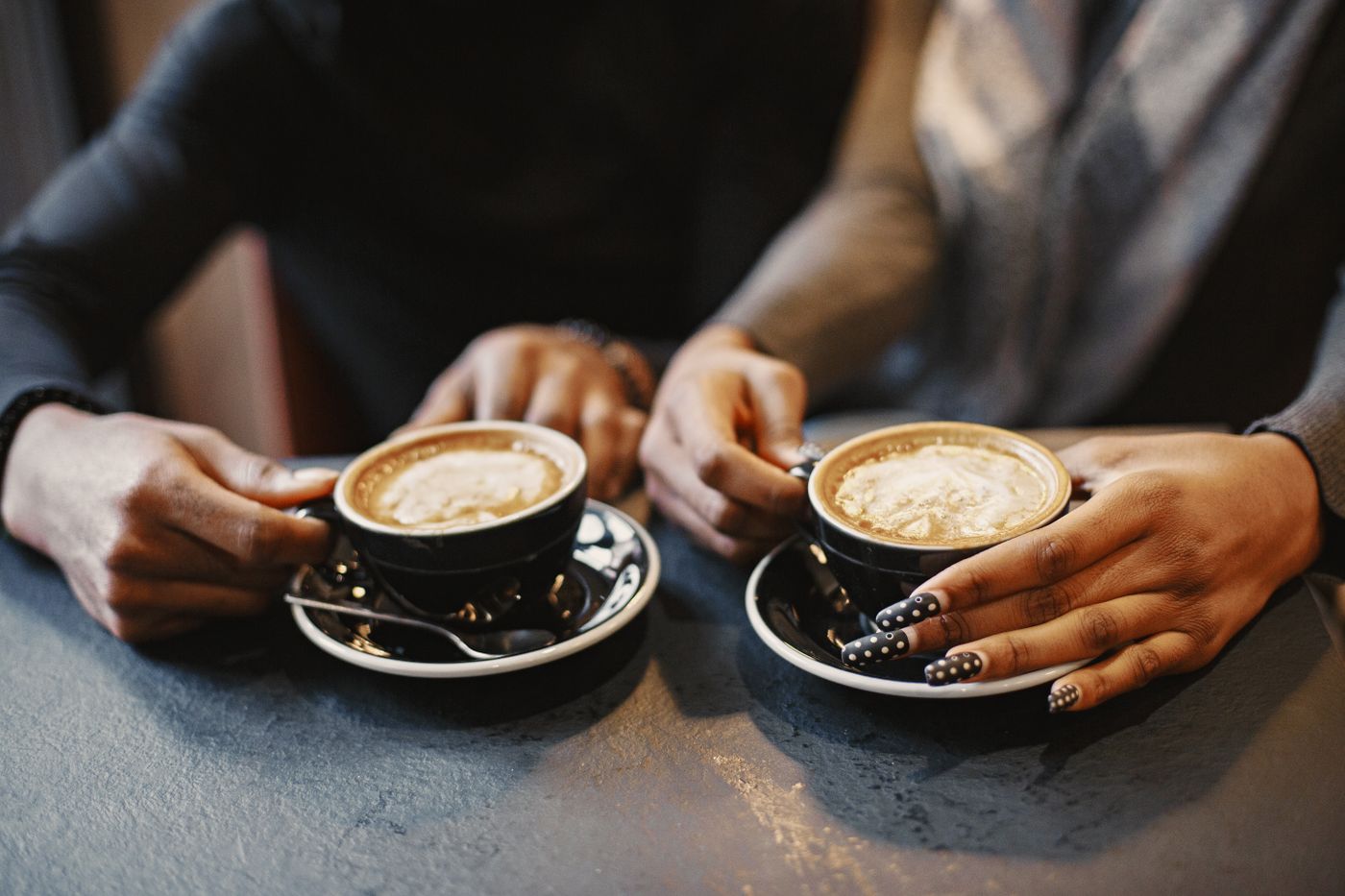 Two people holding hands beside coffee cups
