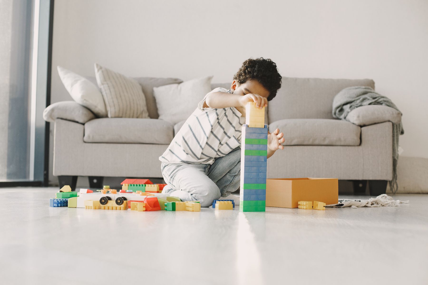 A child building a colorful tower with toy blocks in a bright play space