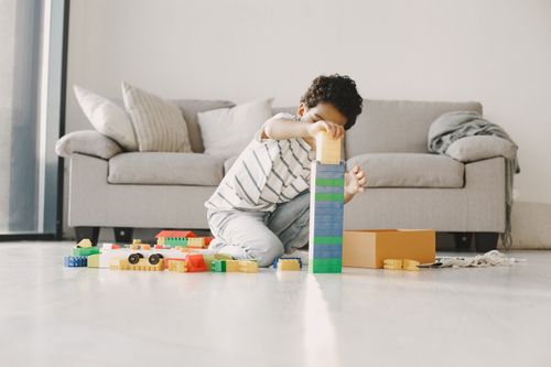 Free Young boy playing with colorful blocks on the floor in a cozy living room, focused and creative. Stock Photo