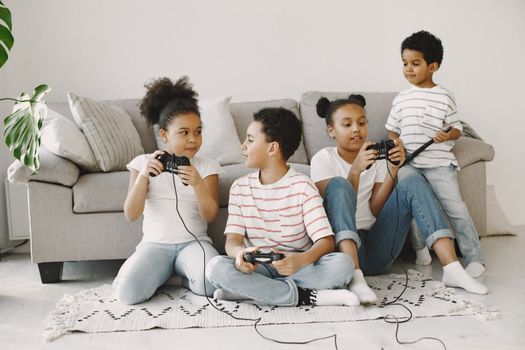 Four children playing video games together in a cozy living room setting.
