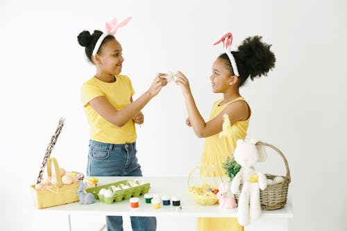 Girls in Yellow Dress Standing beside a Girl in Yellow Shirt and Blue Denim Pants