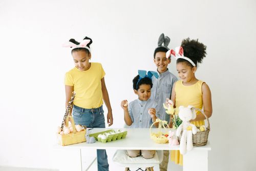 Free Four children wearing bunny ears enjoy decorating Easter eggs at a table. Stock Photo