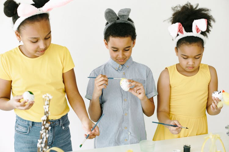 Portrait Of Kids Wearing Bunny Ears Hairbands And Painting Easter Eggs