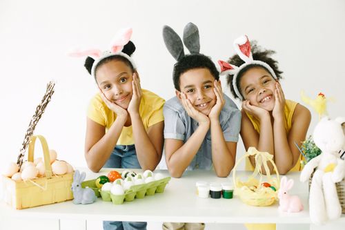 Free Children wearing bunny ears enjoying Easter egg decoration together. Stock Photo