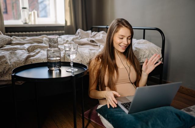 A person waving at a laptop screen during a video call