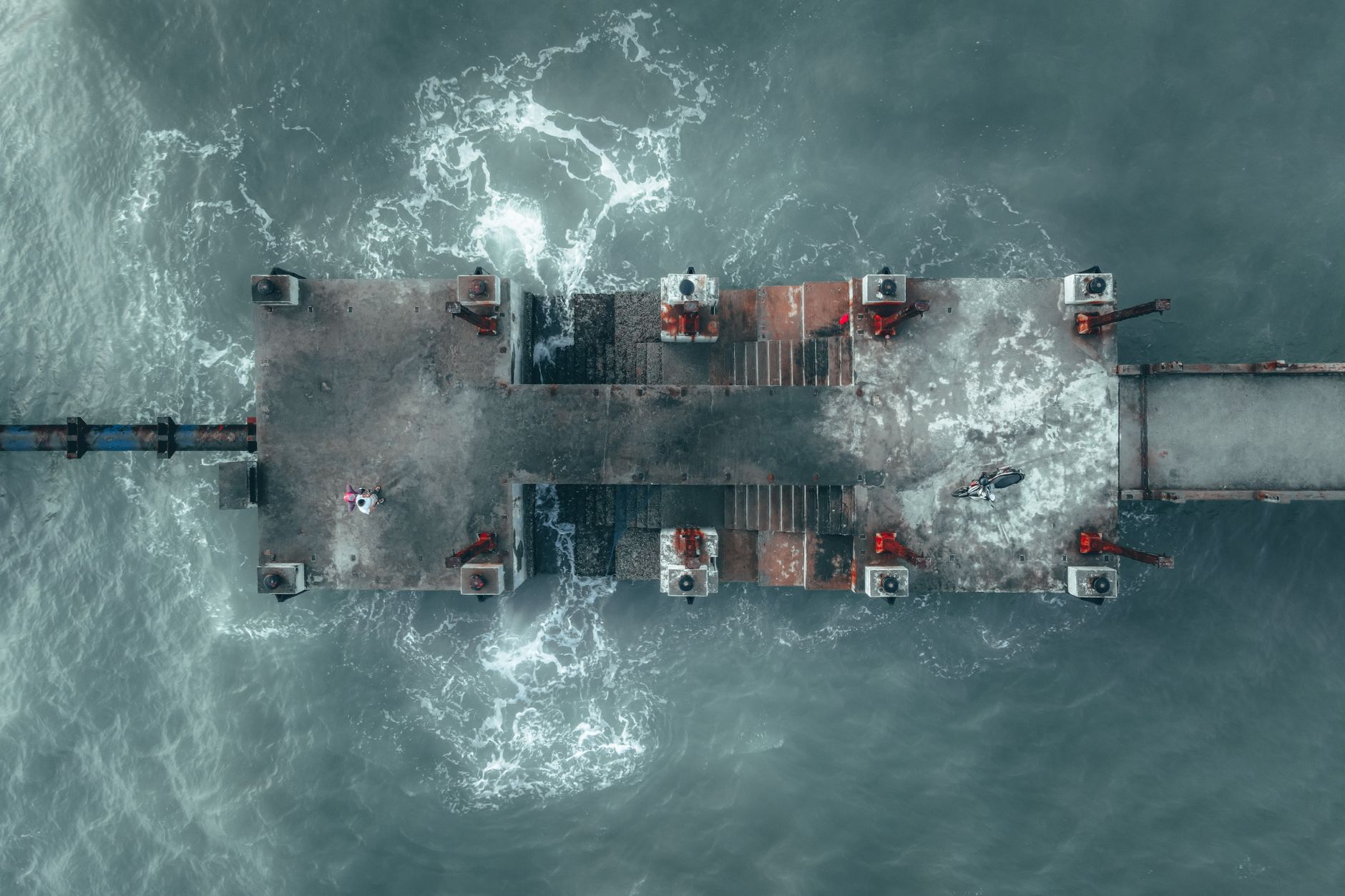 Aerial shot of a platform over the sea in Malaysia, showing water motion and industrial structure.