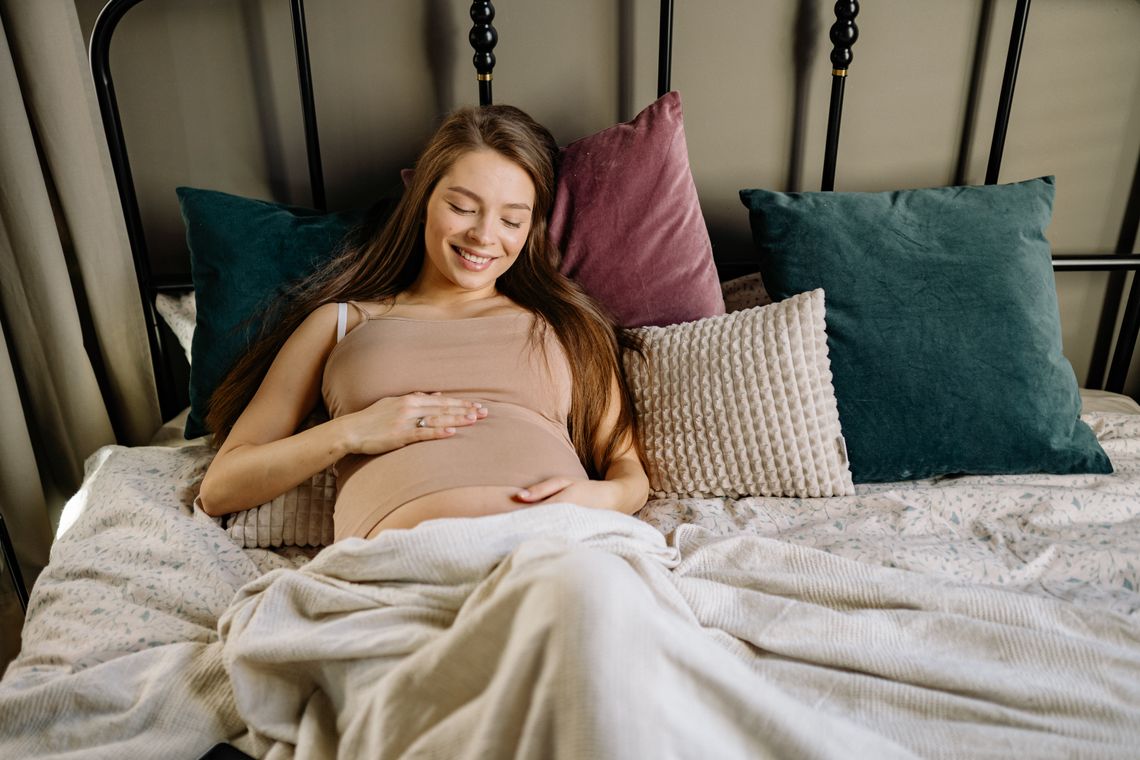 Pregnant woman resting comfortably on a bed with supportive pillows
