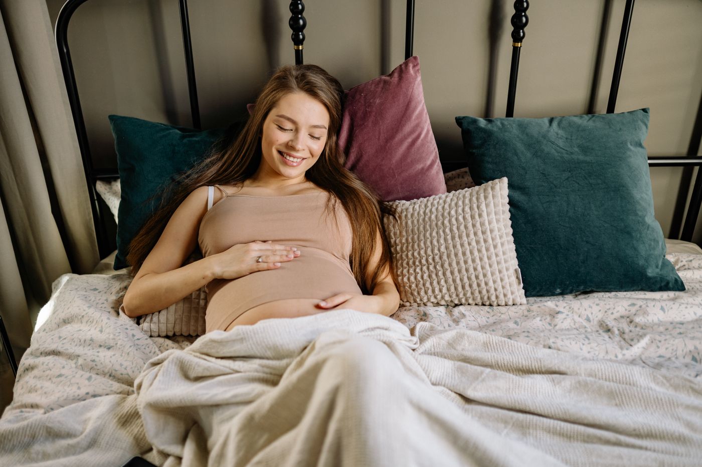 Future maman souriante se reposant au milieu de coussins moelleux