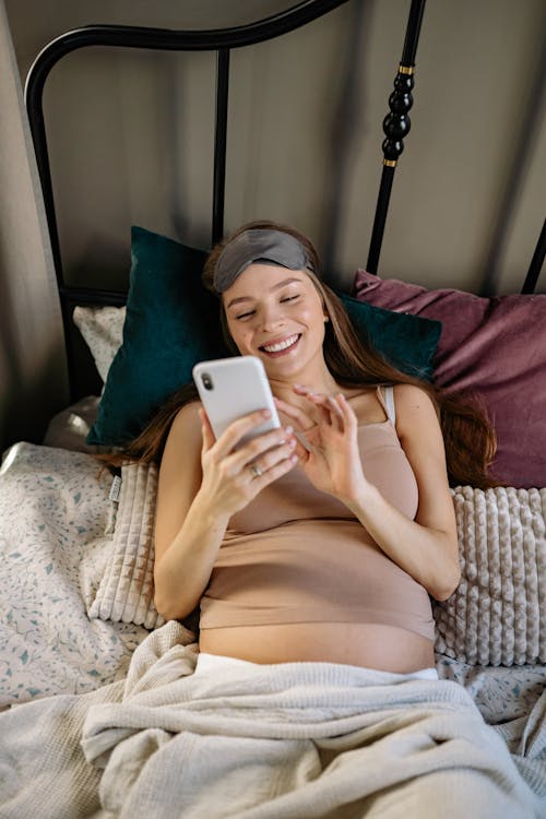 Free A Woman Smiling While Using Her Iphone  Stock Photo