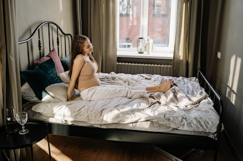 Free A Pregnant Woman Sitting on a Bed Stock Photo