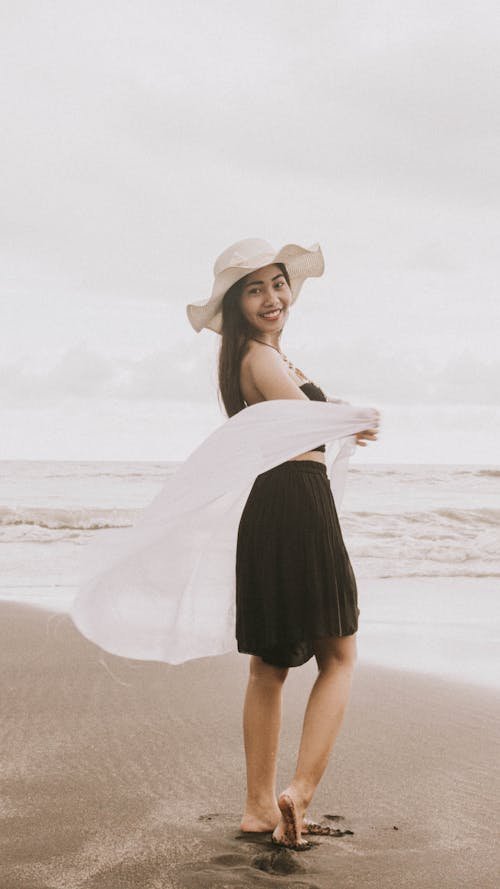 A Woman Wearing a Black Dress While Standing on a Beach
