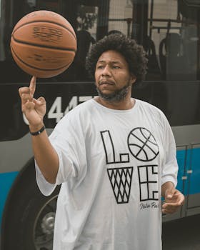 African American man skillfully spins a basketball on his finger in an urban setting.