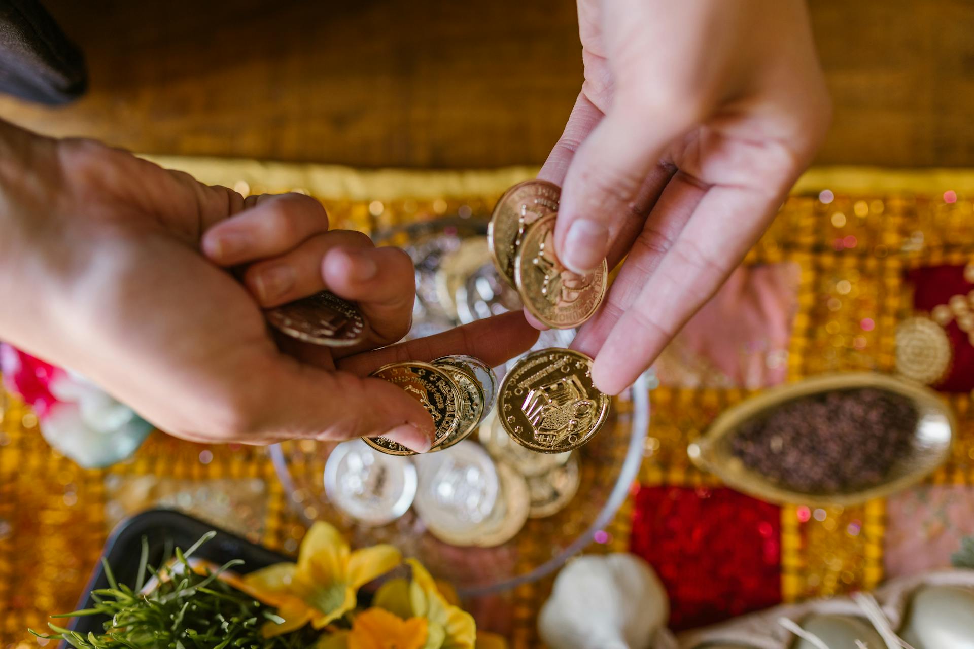 Close-up of hands exchanging gold coins during a vibrant Nowruz celebration, rich with traditional decorations.