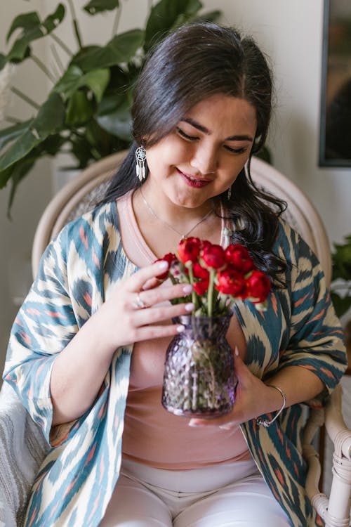 Woman Holding A Vase With Red Flowers