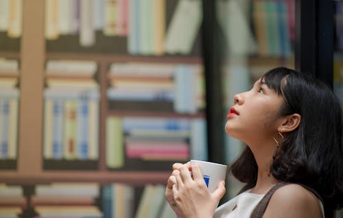 Woman Wearing White Shirt Looking on Top Holding White Ceramic Mug