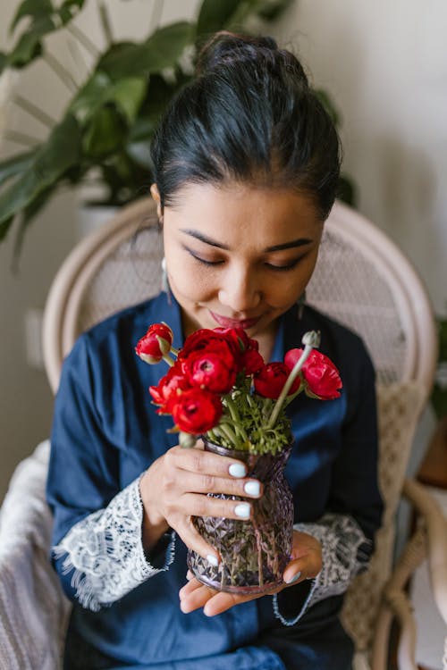 Woman Smelling A Bunch Of Red Flowers