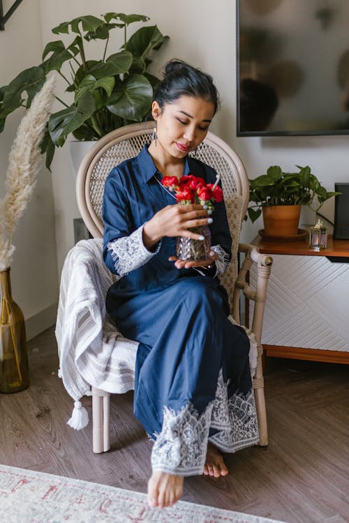 Woman Holding A Vase Of Red Flowers