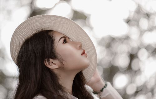Free Portrait of a young woman with a hat, creating a dreamy bokeh effect outdoors. Stock Photo