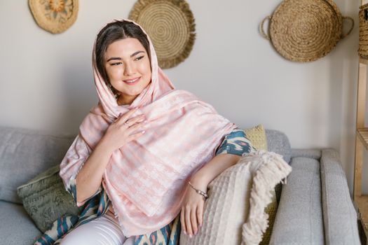 Elegant woman with headscarf smiling indoors, celebrating Nowruz.