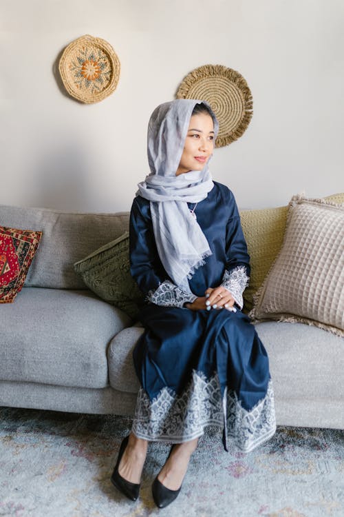 Woman In Blue Dress With Headscarf Sitting On A Couch