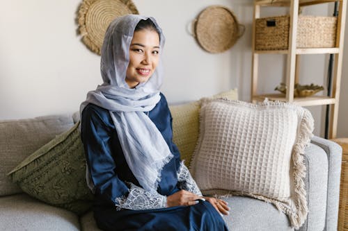 Woman in Blue and White Hijab Sitting on Brown Sofa