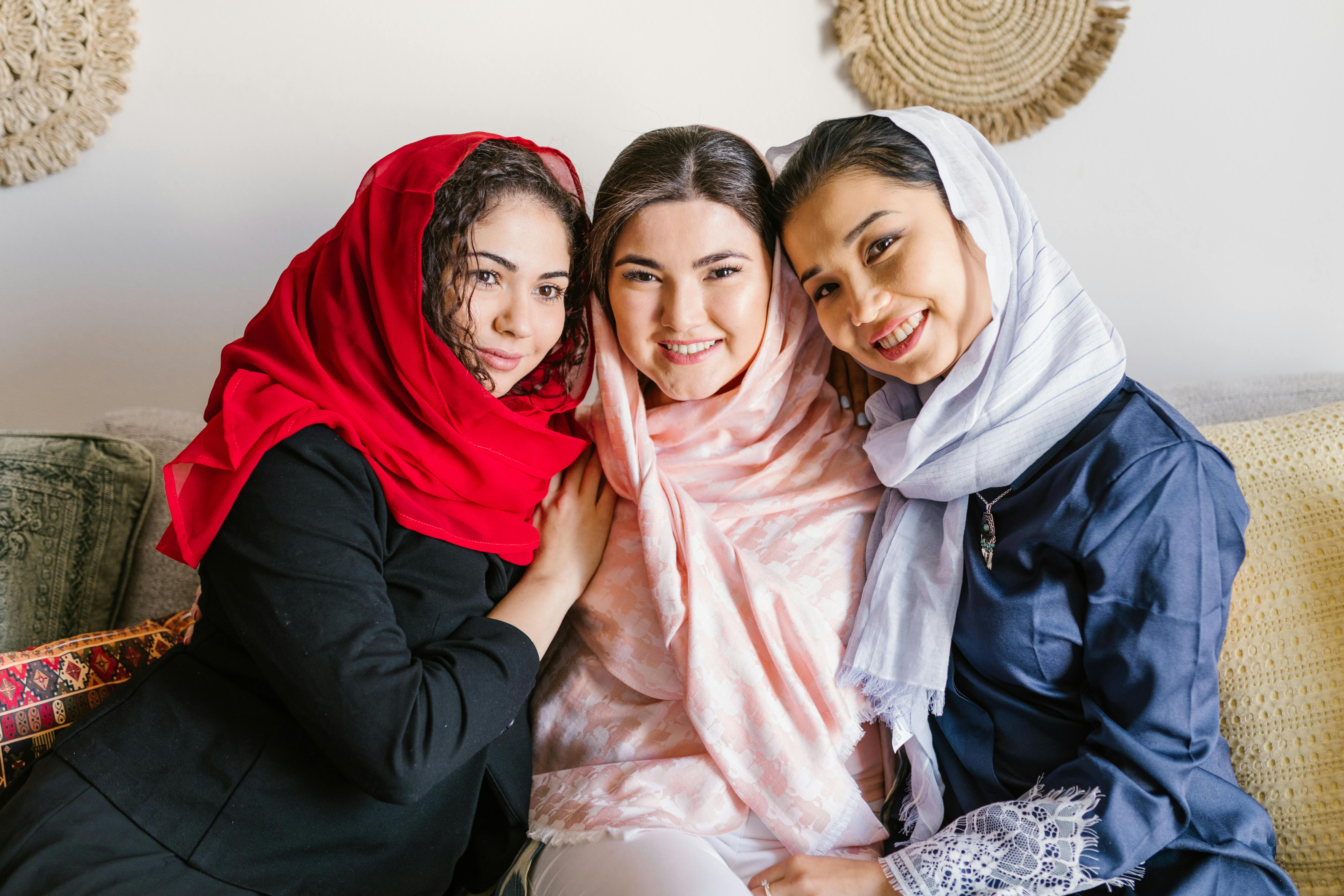 three women wearing hijab sitting on couch