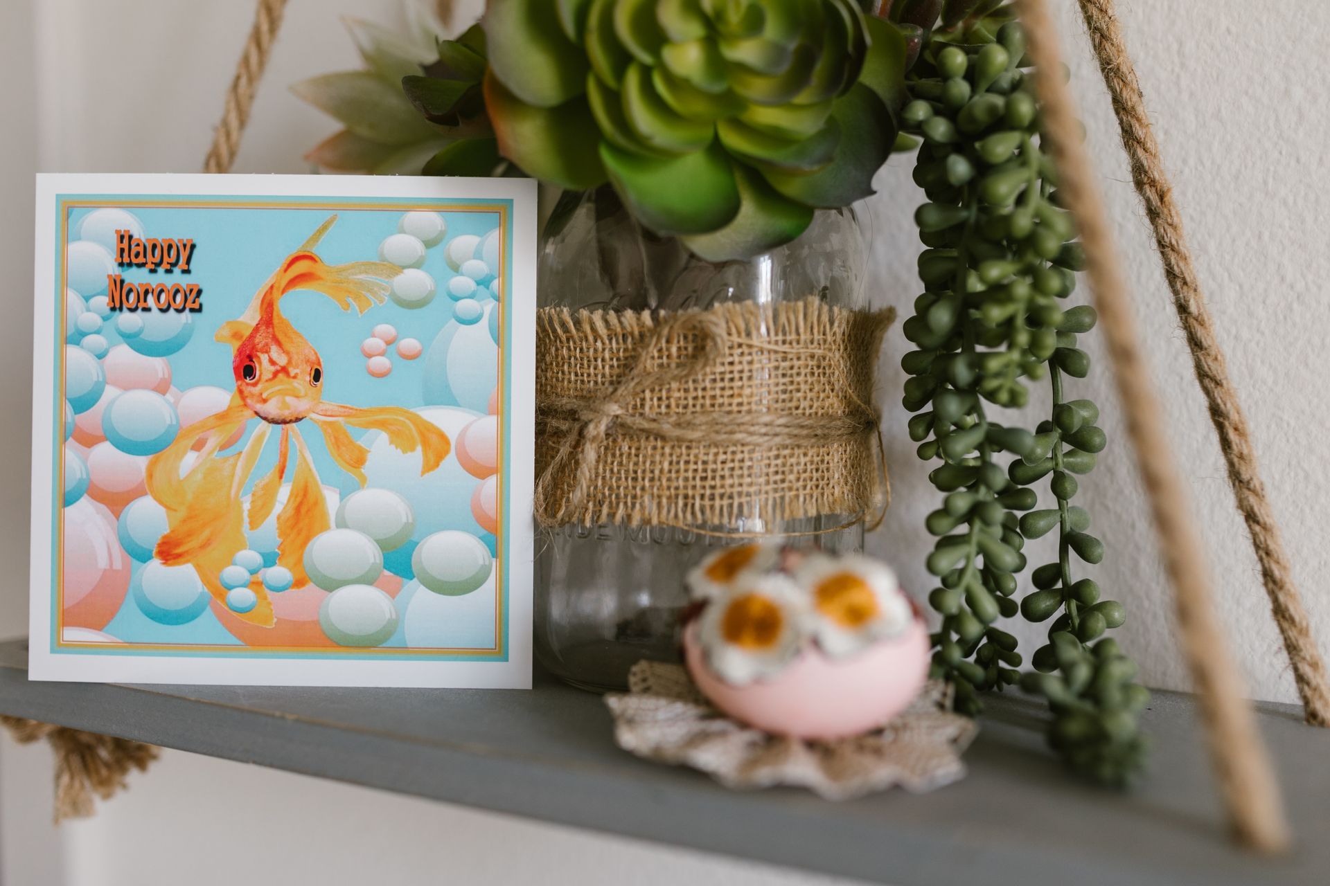 Nowruz celebration card featuring a goldfish with colorful decor on a shelf.